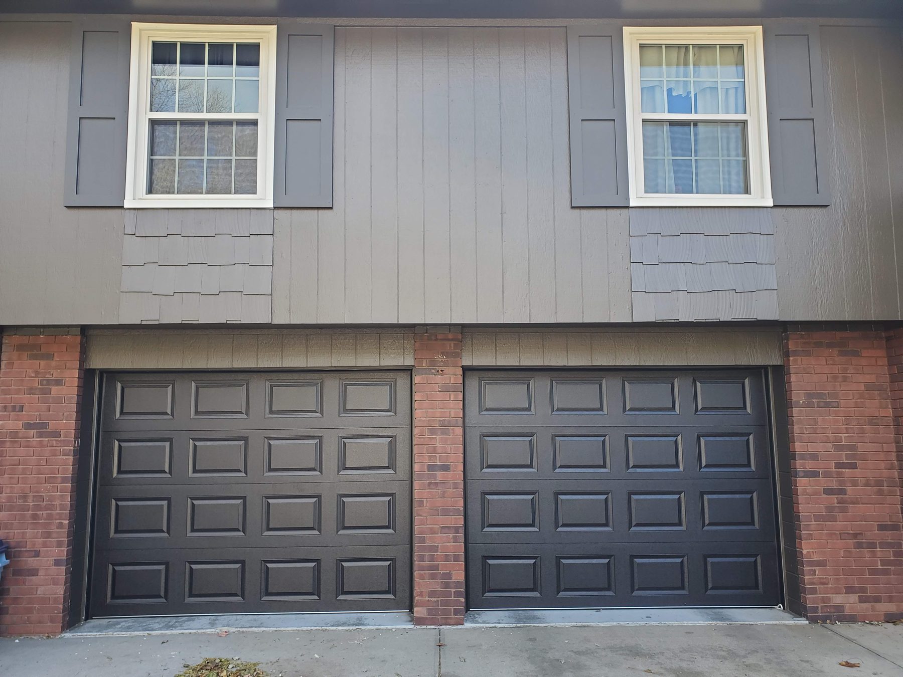 Black raised standard panel residential garage doors on a two-car garage